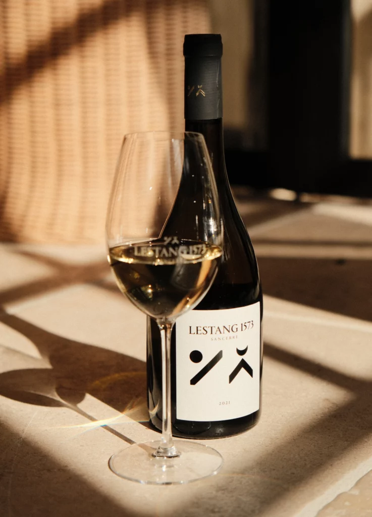 Bouteille cuvée Tradition et verre de vin blanc de Sancerre dans le chai du château