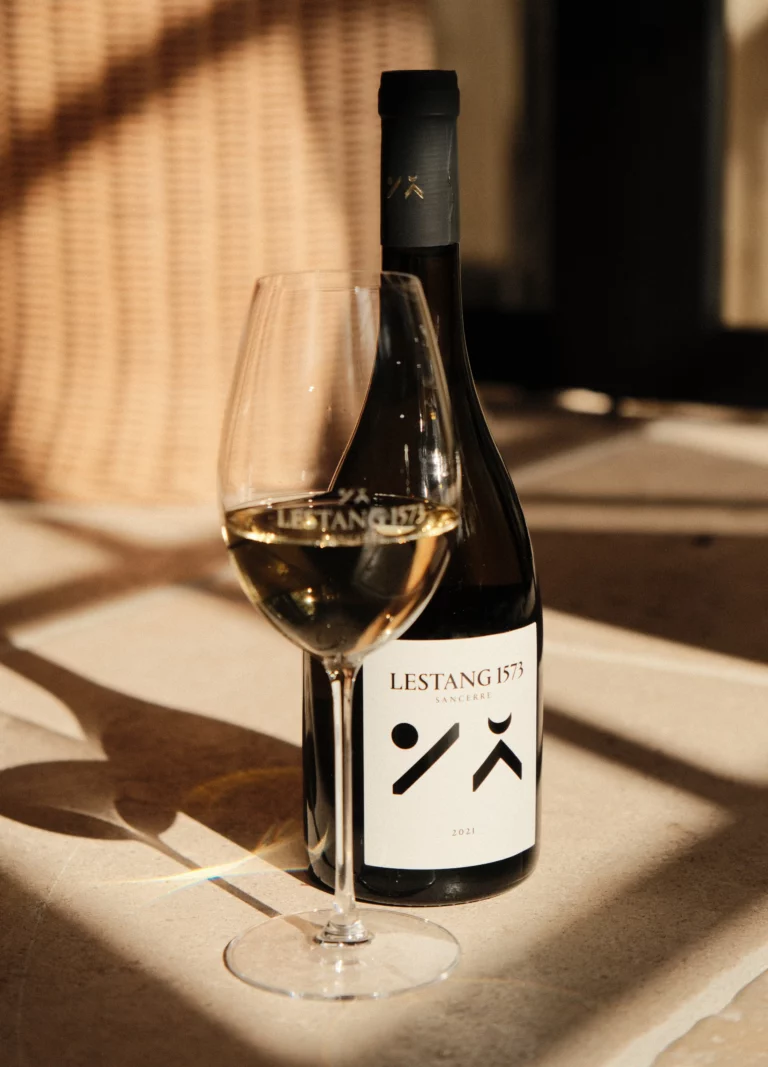 Bouteille cuvée Tradition et verre de vin blanc de Sancerre dans le chai du château